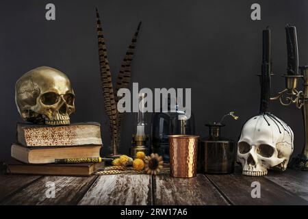 Nature morte dans le style gothique de fleurs séchées, crânes humains, livres vintage, récipients en verre et bougies éteintes Banque D'Images