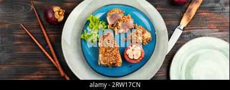 Steak de thon cuit au four dans une panique de noix avec un mangoustan sur la table en bois rustique. Pose à plat. Banque D'Images