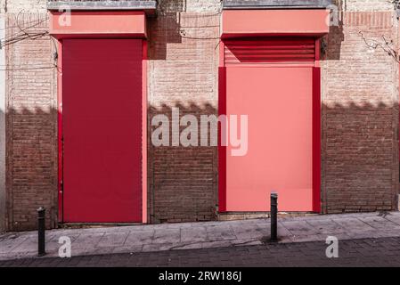 Façade d'un local commercial de couleur rougeâtre sur une rue avec des bornes Banque D'Images