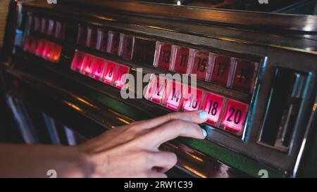 Juke-box de musique américaine vintage avec boutons illuminés, processus de choix de la composition de la chanson, juke-box rétro à l'ancienne avec disques vinyles musicaux b Banque D'Images