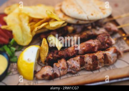 Vue de Souvlaki sur une assiette - plat de cuisine grecque traditionnelle avec un poulet barbecue grillé avec frites et sauce tzatziki servi dans un café taverne Banque D'Images