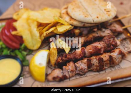 Vue de Souvlaki sur une assiette - plat de cuisine grecque traditionnelle avec un poulet barbecue grillé avec frites et sauce tzatziki servi dans un café taverne Banque D'Images