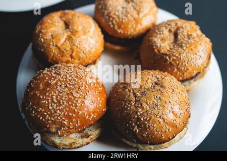 Processus de cuisson et de griller des burgers de bœuf sur le festival de la nourriture de rue en plein air, vue des mains du chef dans des gants avec une variété d'ingrédients sur un sto de gril Banque D'Images