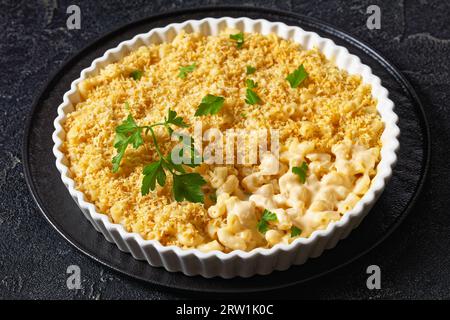 mac cuit au four et fromage saupoudré de chapelure panko et de persil frais dans un plat allant au four sur une table en béton Banque D'Images