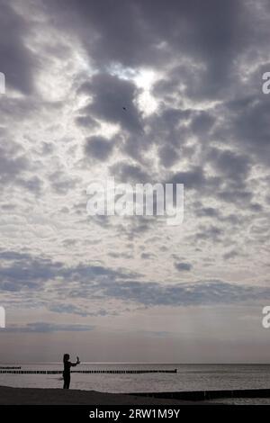 07.09.2022, Allemagne, Mecklembourg-Poméranie occidentale, Wustrow - Silhouette : Femme debout sur la plage sous un ciel couvert. 00S220907D080CAROEX.JPG [ Banque D'Images