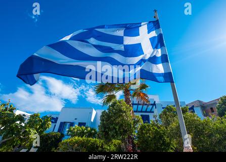 Drapeau de la Grèce sur mât de drapeau agitant sur fond de rue Banque D'Images