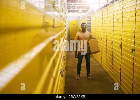 Le gars afro-américain en jeans se tient avec une boîte en carton près des conteneurs Banque D'Images