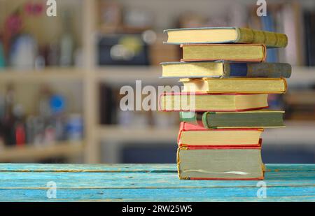Pile de livres avec fond de bibliothèque flou, lecture, apprentissage, éducation ou concept de bureau à domicile Banque D'Images