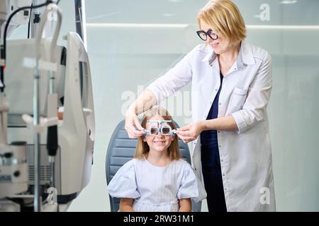 Optométriste amical effectuant un test de réfraction sur une petite fille Banque D'Images