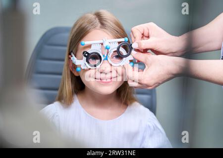 Ophtalmologiste qualifié effectuant un test de réfraction subjectif sur l'enfant Banque D'Images