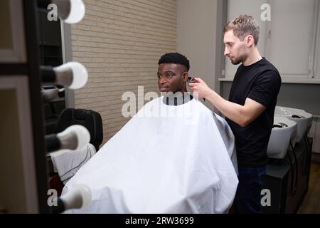 Un Afro-américain se fait couper les cheveux dans un salon de coiffure Banque D'Images