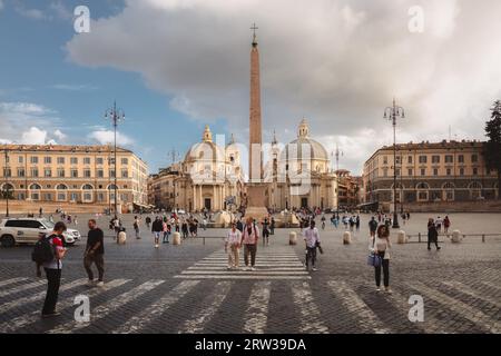 Rome, Italie - 28 août 2023 : les touristes traversent un passage piéton à côté des églises baroques et un obélisque dans la célèbre Piazza del Popolo i. Banque D'Images