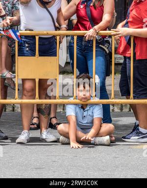 Jeune garçon reposant son menton entre une clôture tout en regardant un défilé du jour de l'indépendance du Costa Rica à San José. Banque D'Images