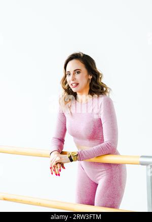 Slim ballerina femme fille en survêtement rose. Étirement à la machine de ballet, mettant en valeur la flexibilité athlétique de danse. Danseur s'entraîne dans la salle de danse de Fitne Banque D'Images