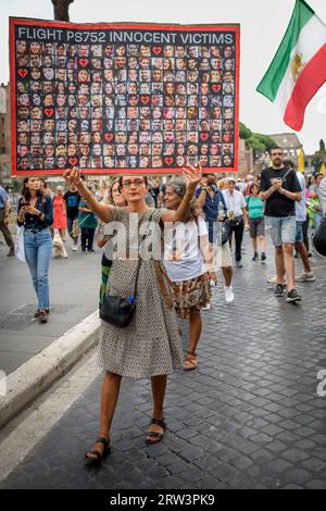 Rome, Italie. 16 septembre 2023. Une iranienne montre le panneau avec des photos des victimes innocentes du vol PS752 (vol commercial abattu à Téhéran le 8 janvier 2020 par les Gardiens de la révolution iraniens avec au moins deux missiles) lors de la manifestation commémorant la mort de Mahsa Amini à Rome. arrêté à Téhéran le 13 septembre 2022 par la police religieuse pour non-respect de la loi sur le port obligatoire du voile. Elle est décédée dans des circonstances suspectes après trois jours dans le coma le 16 septembre 2022 à l'âge de 22 ans. Crédit : ZUMA Press, Inc./Alamy Live News Banque D'Images