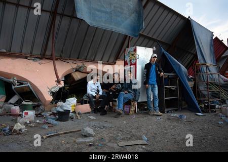 Un groupe d’hommes est assis devant ce qui était autrefois un magasin de station-service complètement aplati par le tremblement de terre dans la ville d’Idni dans l’Atlas marocain. Le tremblement de terre qui a frappé le Maroc vendredi 8 septembre a été le pire de l'histoire du pays, faisant plus de 2 000 morts. Banque D'Images