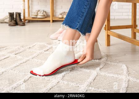 Femme qui s'attache à la semelle intérieure orthopédique rouge à la maison Banque D'Images