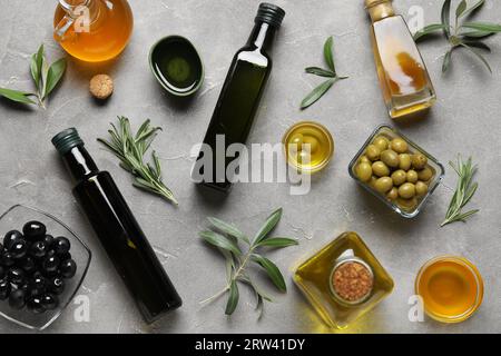 Bouteilles et bols d'huile d'olive fraîche sur fond gris Banque D'Images