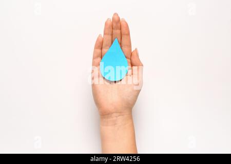 Main féminine avec goutte de papier sur fond blanc. Journée mondiale de la poliomyélite Banque D'Images