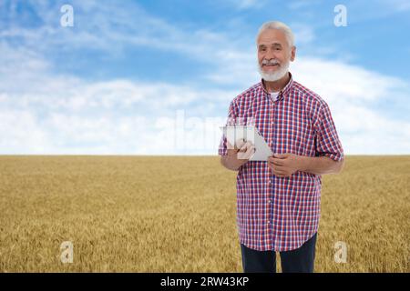 Agriculteur avec tablette dans le champ. Saison de récolte Banque D'Images