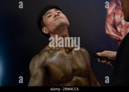 Bangkok, Thaïlande. 16 septembre 2023. L'assistant de l'athlète peint le bronzage sur le corps d'un athlète de culturisme, avant de monter sur scène pour concourir aux Championnats de muscle et de physique de Thaïlande 2023 le 16 septembre 2023. Au Central Rama 2 Department Store, Bangkok, Thaïlande. (Image de crédit : © Teera Noisakran/Pacific Press via ZUMA Press Wire) USAGE ÉDITORIAL SEULEMENT! Non destiné à UN USAGE commercial ! Banque D'Images