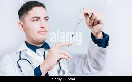 Beau médecin tenant la seringue avec antidote sur fond isolé. Gros plan du médecin tenant la seringue et l'antidote isolés Banque D'Images