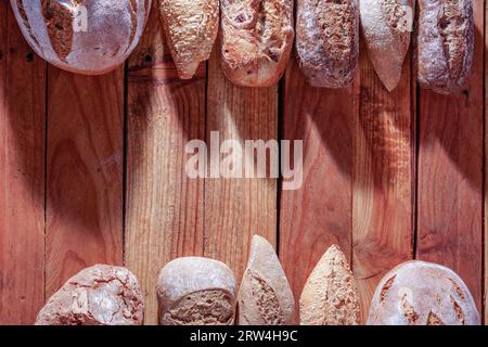 Différents types de pains et pains de pain artisanal rustique dans une rangée sur une table en bois avec un espace de copie au centre Banque D'Images