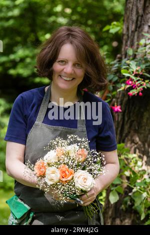 Jardinier avec bouquet de fleurs et tablier dans un jardin, jardinier avec bouquet de fleurs et tablier dans un jardin Banque D'Images