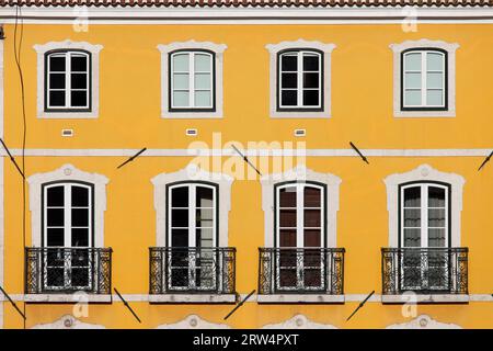 Maison traditionnelle avec façade jaune et grandes fenêtres avec balcons à Lisbonne, Portugal Banque D'Images