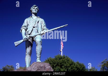 Le Capitaine Parker statue sur Battle Green avec le drapeau américain, Lexington Green, Lexington, Massachusetts Banque D'Images