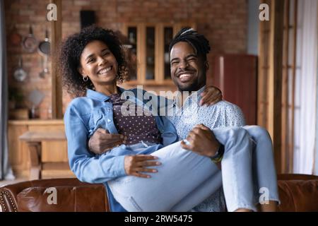 Portrait souriant homme afro-américain portant une femme, regardant la caméra Banque D'Images