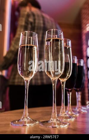 Champagne frais ou vin mousseux blanc, alcool dans un verre, vin rouge sur la table un fond flou de l'intérieur. Banque D'Images