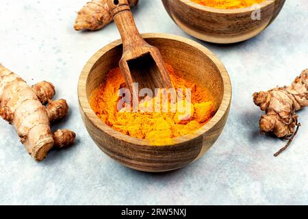 Racine de curcuma fraîche ou Curcuma longa Linn dans un bol en bois et poudre de curcuma. Banque D'Images