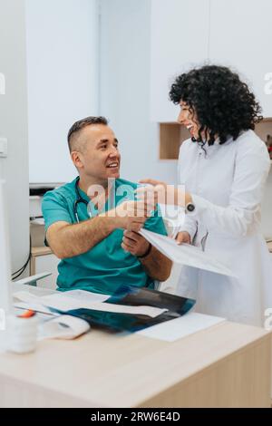 Deux médecins analysent les résultats des tests, discutent des diagnostics et fournissent des conseils médicaux et du soutien dans un cadre clinique intérieur. Banque D'Images