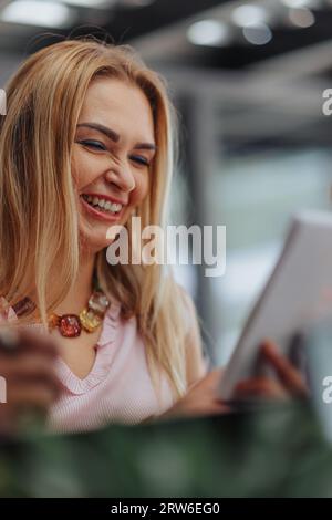 Femme d'affaires concentrée et satisfaite analysant les statistiques, faisant de la paperasse, et souriant dans un bureau moderne. Elle est déterminée, innovante et réussie Banque D'Images