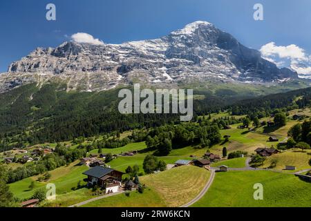 l'eiger au-dessus de grindelwald avec des chalets en bois typiques et des pâturages de ferme Banque D'Images