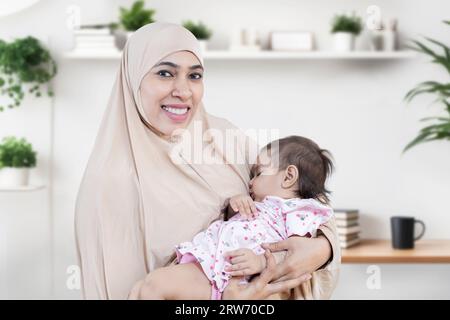 Portrait de jeune mère musulmane souriante portant le hijab tenant son mignon petit bébé. Banque D'Images