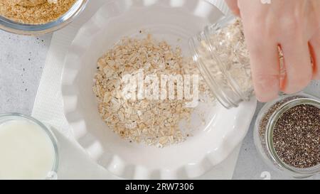 Femme préparant le petit déjeuner. Flocons d'avoine à base d'avoine entière, de farine de lin, de graines de Chia et de lait. Vue rapprochée du dessus Banque D'Images