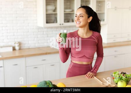 Arabe Jeune femme tenant Smoothie fait de légumes verts à l'intérieur Banque D'Images