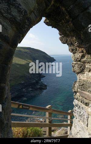 Vue spectaculaire sur la côte à travers une ancienne arche en pierre surplombant la mer turquoise et les falaises en Cornouailles Banque D'Images