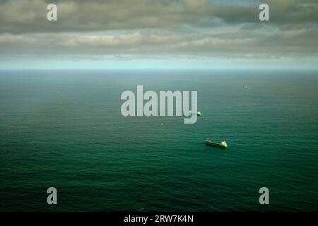 panorama horizontal de deux grands cargos attendant d'entrer dans le port avec leurs arcs pointant vers l'horizon, image dans les tons verts avec dramati Banque D'Images