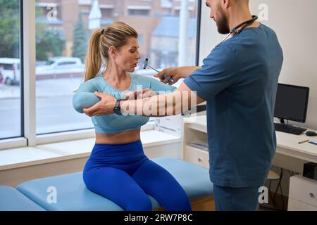 Médecin neurologue concentré vérifiant les réflexes de la femme sportive Banque D'Images