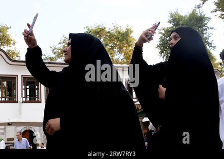 Des femmes musulmanes, portant chacune une burqa, prennent des selfies avec leur smartphone à la mosquée Eyüp Sultan à Istanbul en Turquie Banque D'Images