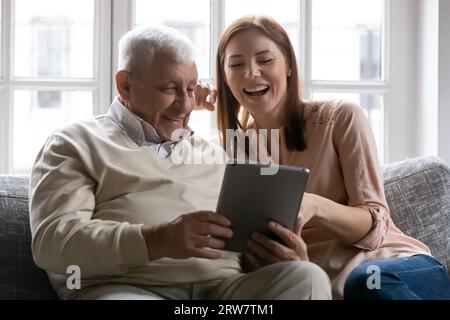 Heureux homme senior et fille adulte utilisant la tablette ensemble Banque D'Images