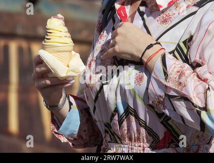 Corps de section médiane de la jeune femme tenant le cône avec la vanille et la crème glacée à la fraise au marché fermier dans la journée chaude ensoleillée. Banque D'Images