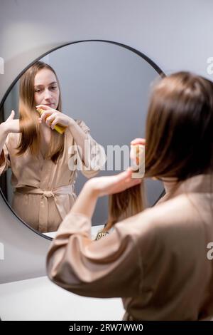 Jeune femme appliquant de l'huile essentielle biologique naturelle sur les cheveux et la peau. Spa à la maison et rituels de beauté. Soins de la peau Banque D'Images