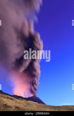 Éruption du volcan Etna vue à l’aube avec de grandes émissions de cendres du cratère avec ciel bleu en arrière-plan ; 13 août 2023 Banque D'Images