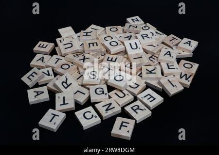 Lake Elsinore, CA, USA - 17 septembre 2023 : vue à mi-angle d'une pile de lettres de tuiles scrabble isolées sur noir. Banque D'Images
