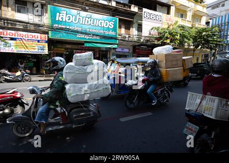 Coursiers à moto avec des boîtes surchargées et des colis dans la rue en Thaïlande. Banque D'Images