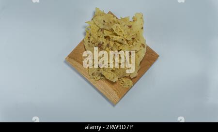 Kacang rempeyek ou peyek. craquelins faits à partir de cacahuètes mélangées avec un mélange de farine de riz, qui sont frits. Servi sur une assiette en bois. Isolé sur fond blanc Banque D'Images